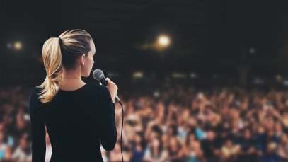 Back of Woman Giving Speech in Front of a Crowd