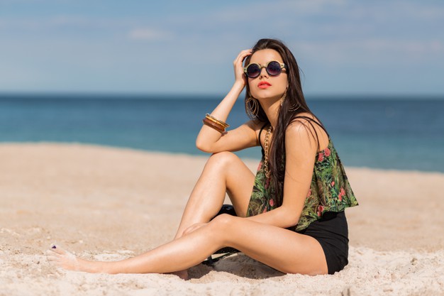 Woman in stylish tropical autfit posing on the beach. Free Photo