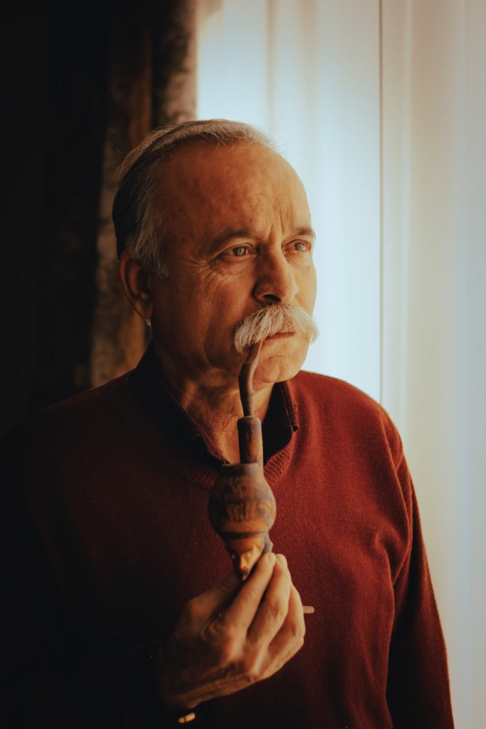 man in red crew neck shirt holding brown hookah