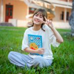 a young girl sitting in the grass holding a book