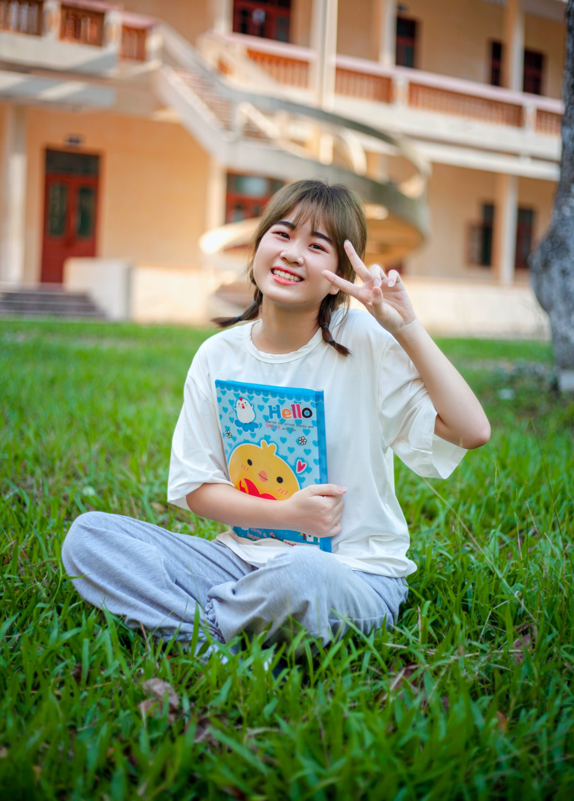 a young girl sitting in the grass holding a book