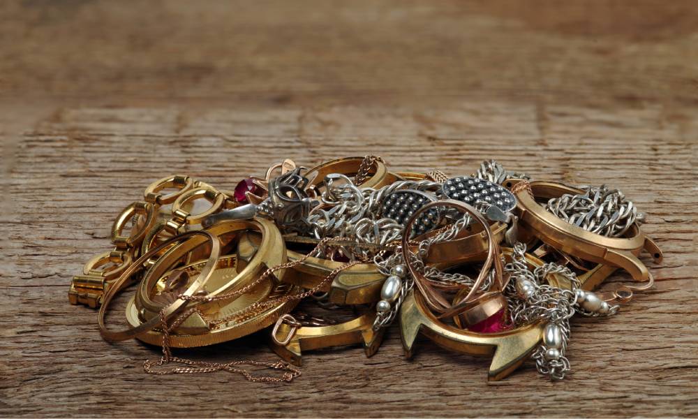 A small pile of tangled gold and silver necklaces and rings on a wooden surface.